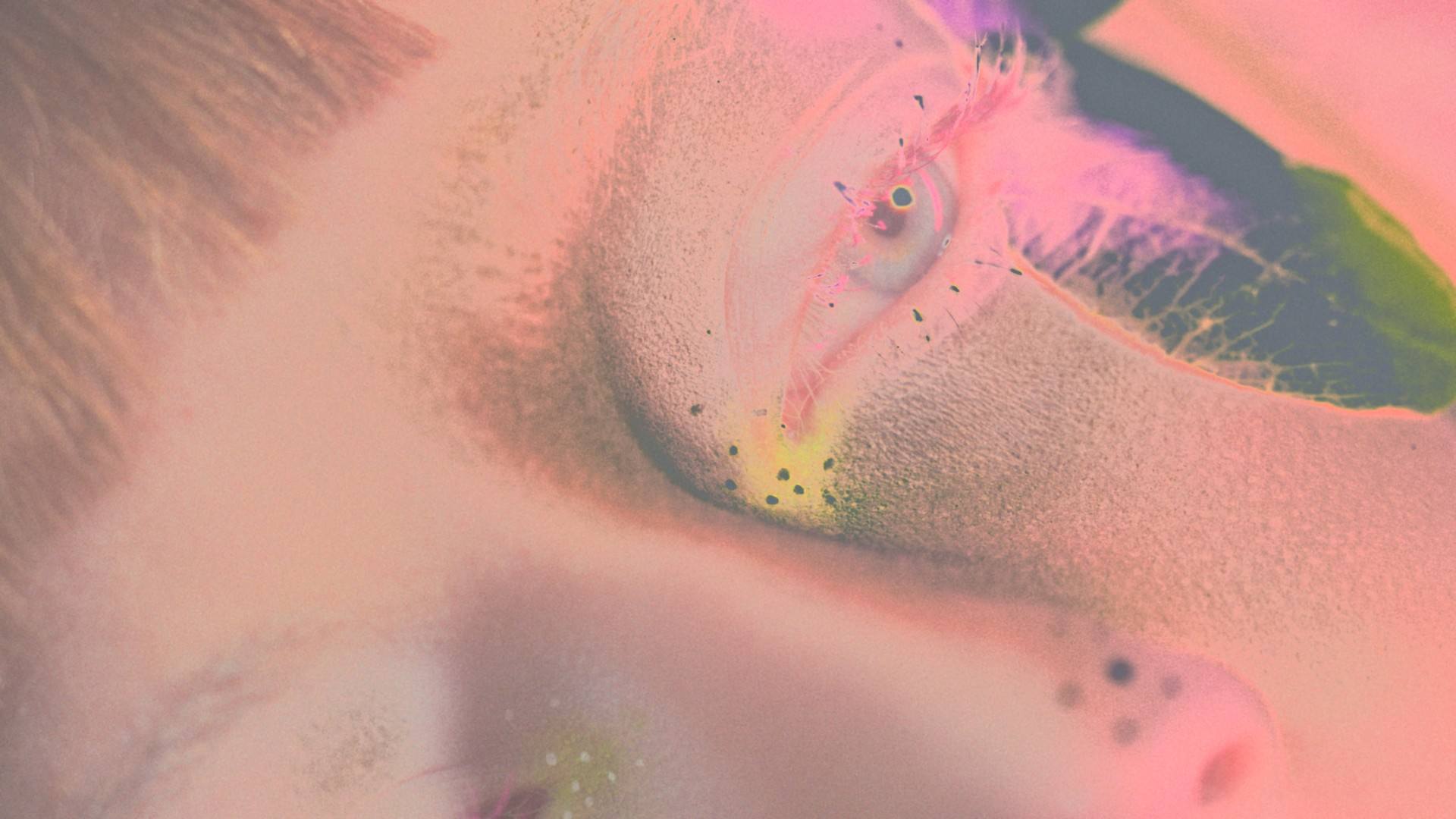 Solarised pastel close-up of an eye with glitter and coloured lashes